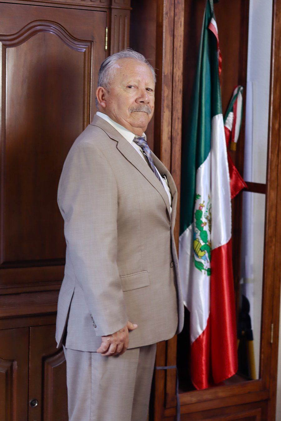 Lic. Ricardo Gutiérrez Ruiz junto a la bandera de México